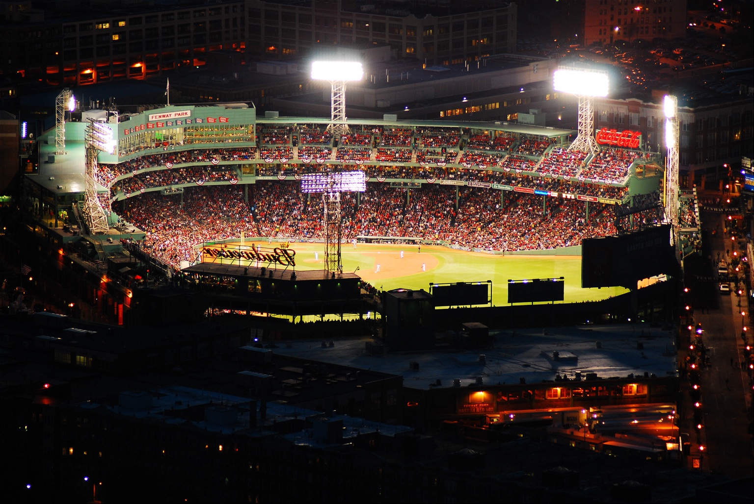 Fenway Park filled with spectators during a nighttime baseball game